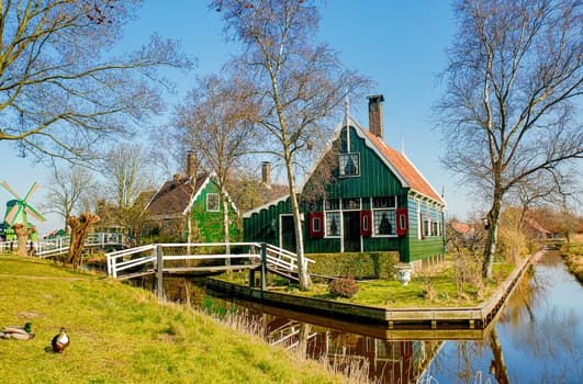Dutch scenery with a historic home on a lake and an antique windmill 