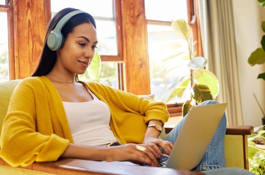 Woman, laptop and remote work, headphones for listening to music while working from home. Female freelancer, copywriter for blog or website with radio or podcast streaming, typing and productivity