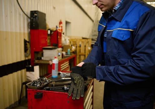 Close-up of a car engineer, mechanic, technician putting on protective work gloves before testing a car in repair shop. Car repair and maintenance concept