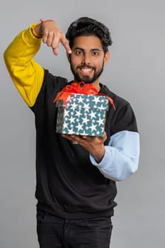 Indian man presenting birthday gift box, offer wrapped present career bonus, celebrating party, sale