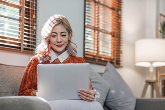 Young woman using laptop while sitting on comfortable sofa, home