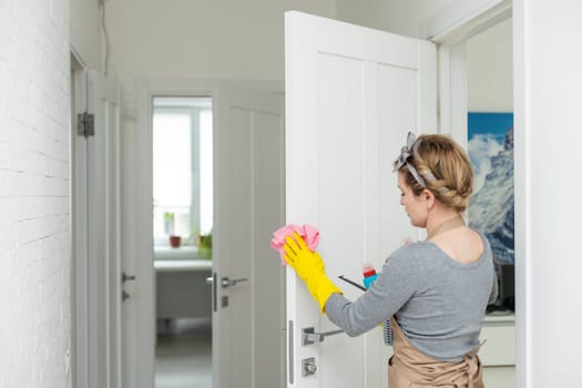 Woman cleaning and polishing the kitchen worktop with a spray detergent, housekeeping and hygiene concept.