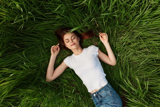 The young woman lies in a green bright grass