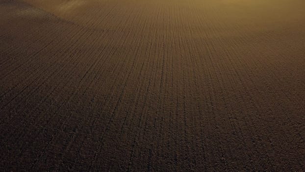Landscape of plowed up land on an agricultural field on a sunny autumn day. Flying over the plowed earth with black soil. Agrarian background. Black soil. Ground earth dirt priming aerial drone view.