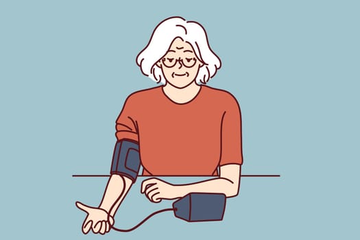 Elderly woman uses tonometer to measure blood pressure and check for symptoms of hypertension