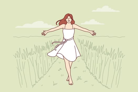 Woman walks along path among tall grass enjoying beautiful nature in rural or farming area