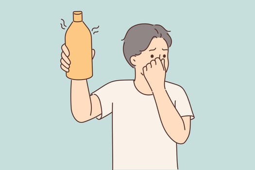 Man covers nose holding bottle of drink or milk that has expired and begun to ferment