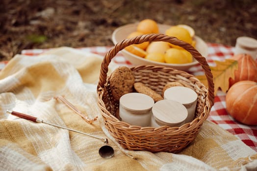 Basket with many aromatic candles on picnic mat in autumn forest