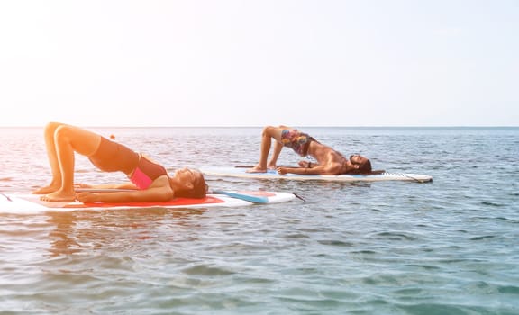 Woman man sup yoga. Happy young sporty couple practising yoga pilates on paddle sup surfboard. Female stretching doing workout on sea water. Modern family outdoor summer sport activity.