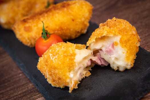Homemade traditional Spanish croquettes or croquetas on a black plate with fork, Tapas food