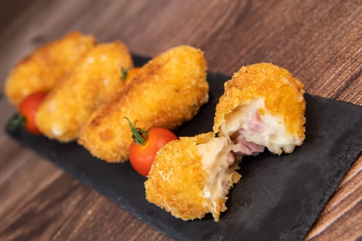 Homemade traditional Spanish croquettes or croquetas on a black plate with fork, Tapas food