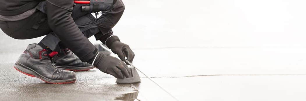 Ground wire. A worker lays a ground cable on the roof of a building. Electrician fixing aluminum wire for grounding solar panels