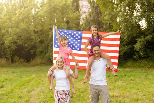 happy family with the flag of america USA at sunset outdoors