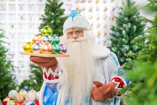 Russian santa claus holds decorations for the christmas tree in the store.