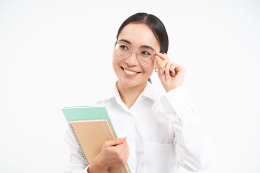 Smiling woman professional, asian female teacher with glasses, looking confident, standing over white background