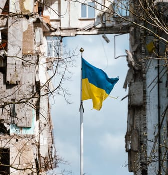 Flag of Ukraine against the background of a destroyed building in Ukraine