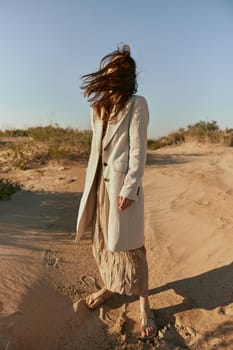 stylishly dressed woman stands posing in the desert in windy weather. High quality photo