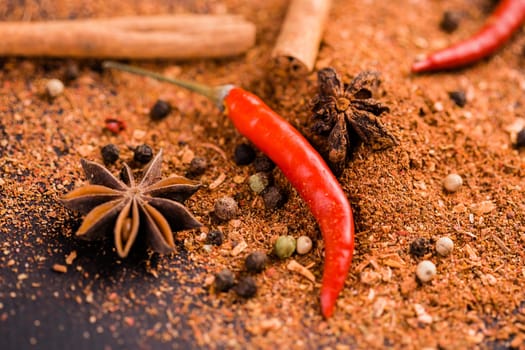 Close-up of spicy red capsicum cinnamon and ground pepper lie on the table. Spicy food concept and oriental cuisine