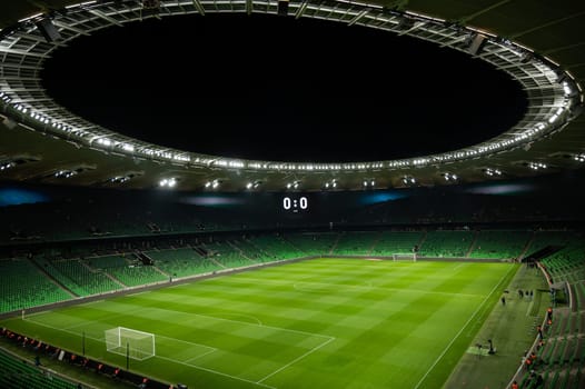 An open football stadium with empty stands with green seats.
