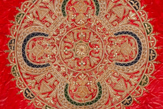 A closeup shot of national ornaments and patterns of Central Asia on red fabric