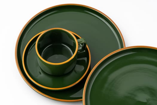 A set of dark green ceramic tableware with orange outlines on a white background