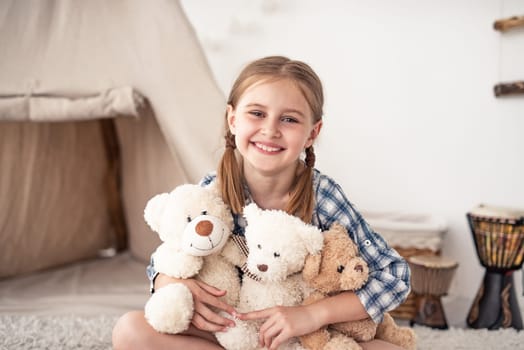 Little girl hugging plush teddies and smiling