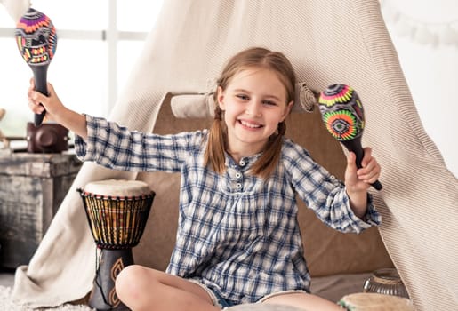 Little girl with maracas and djembe drums