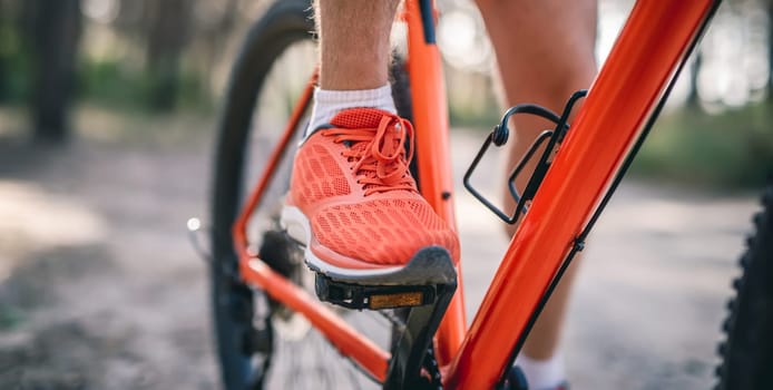 Legs of man in sneakers riding bicycle