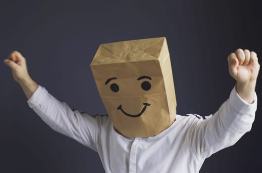 Cheerful man with a bag on his head, with a drawn smiley.