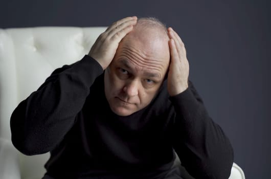 The man is concerned about the problem of hair loss and baldness.
