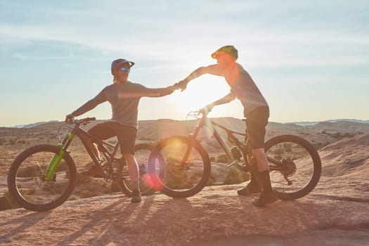 The determination to ace the race. Full length shot of two young male athletes fist bumping while mountain biking in the wilderness.