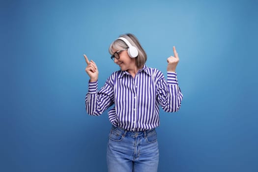 bright cheerful 60s woman with gray hair with headphones without wire on a bright studio background