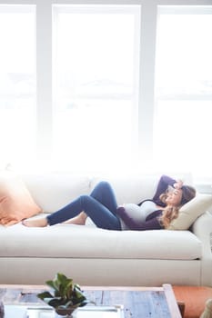 Taking a nap with baby. Full length shot of an attractive young pregnant woman taking a nap on the sofa at home.