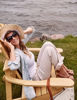 Relaxation is the greatest weapon against stress. a beautiful young woman relaxing on a chair next a lake.