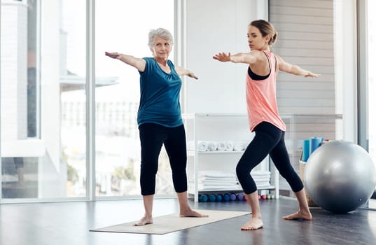 Its all about balance. a fitness instructor helping a senior woman during a yoga class.