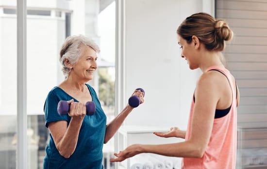 Putting in some muscle-strengthening moves. a fitness instructor helping a senior woman with some weightlifting exercises.