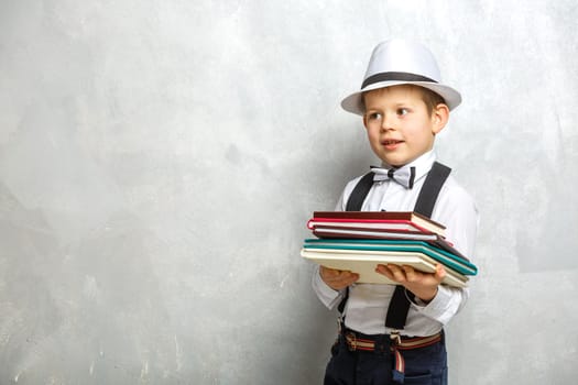 Elementary school student carrying notebooks over a gray background