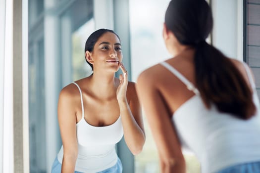 You have to remain vigilant in caring for your skin. an attractive young woman inspecting her skin in front of the bathroom mirror.