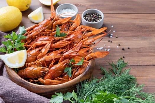 cooked crawfish in wooden bowl with lemons and spices on wooden background