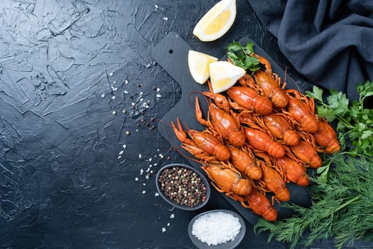 cooked crawfish on platter with lemons and spices on dark background