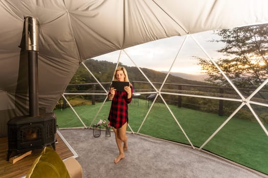 A woman sits in a geo dome glamping tent, looks at the nature.