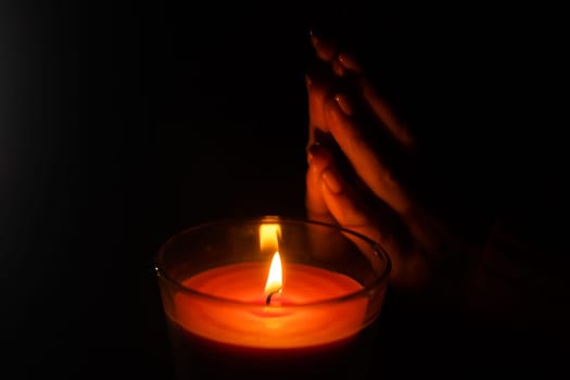 a woman warms her hands on a burning candle