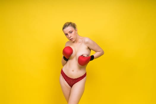 Seductive young and fit female fighter posing in gloves in studio