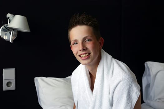 A cute teenage boy with a white towel draped over himself.