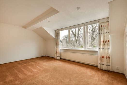 an empty bedroom with a large window and curtains