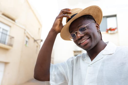 Young African American man wearing a hat on vacations looking at camera.
