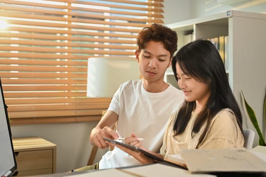 Image of tutor giving private educational lesson to teenage asian girl. Homeschooling and education concept
