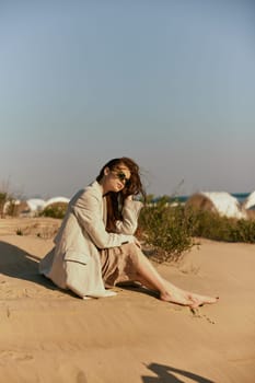 a woman on the beach sits in a stylish jacket during her vacation