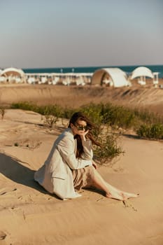 a woman on the beach sits in a stylish jacket during her vacation