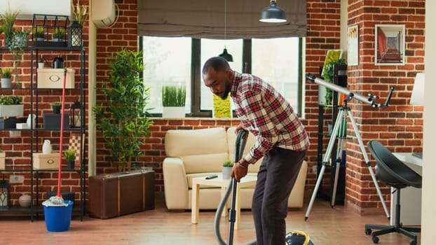 African american partner using vacuum to clean dust in living room